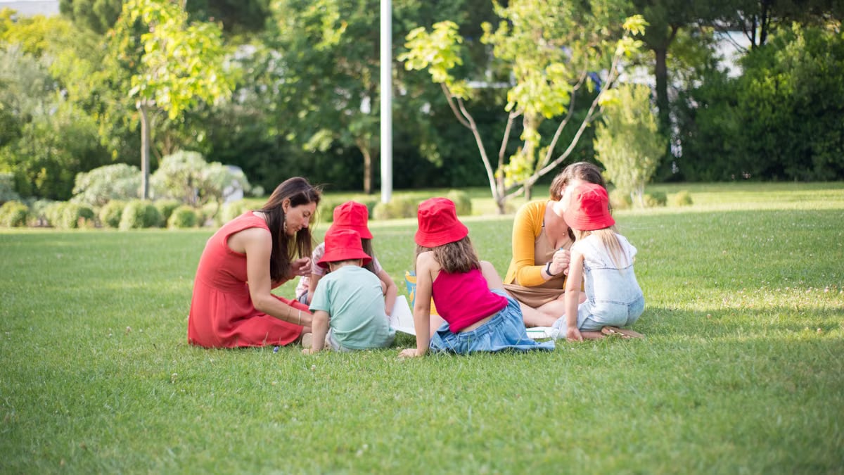 A family enjoys a summer picnic outdoors, bonding and relaxing in a sunny park setting.